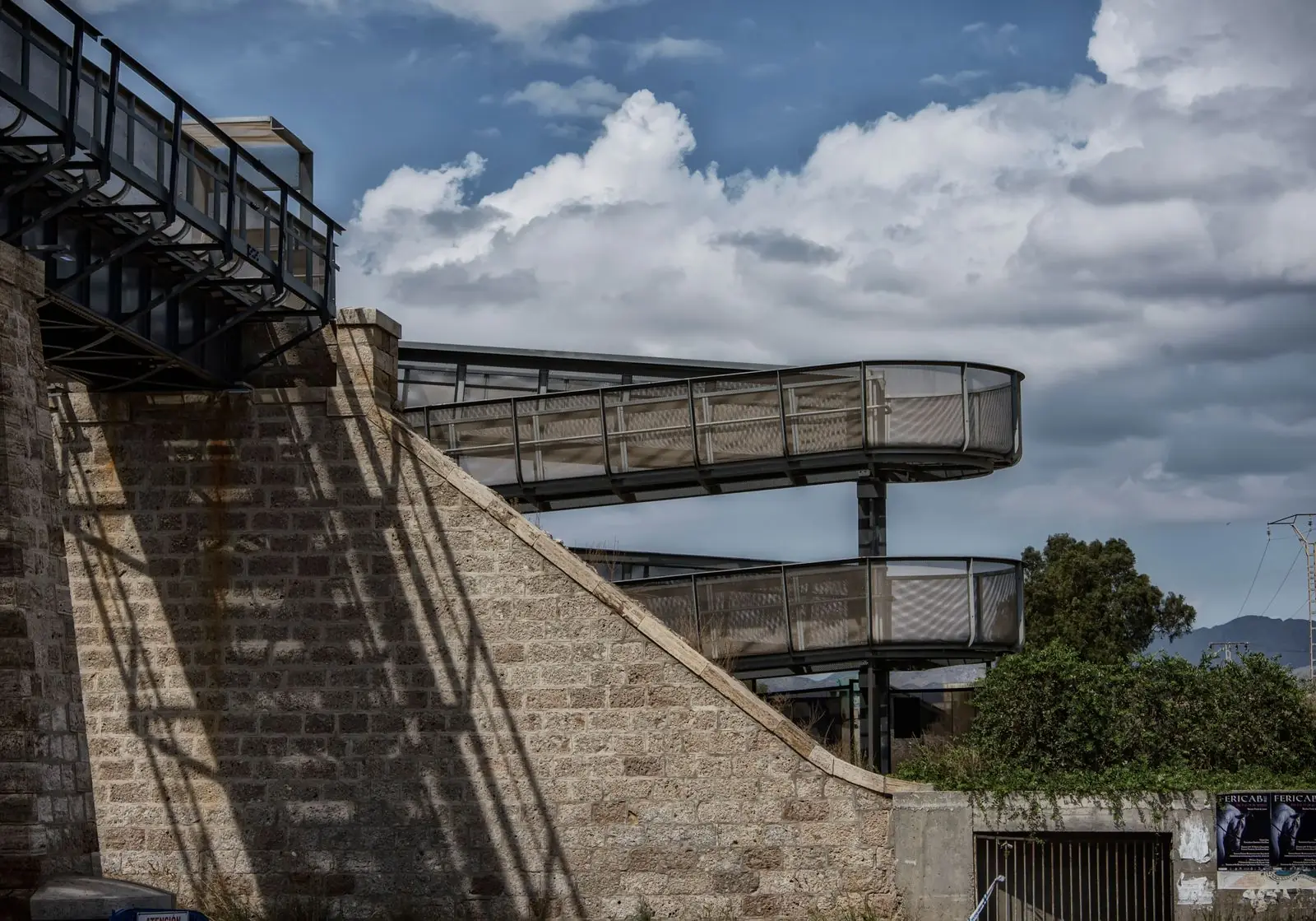 Gebogen stalen loopbrug langs een stenen muur in Águilas
