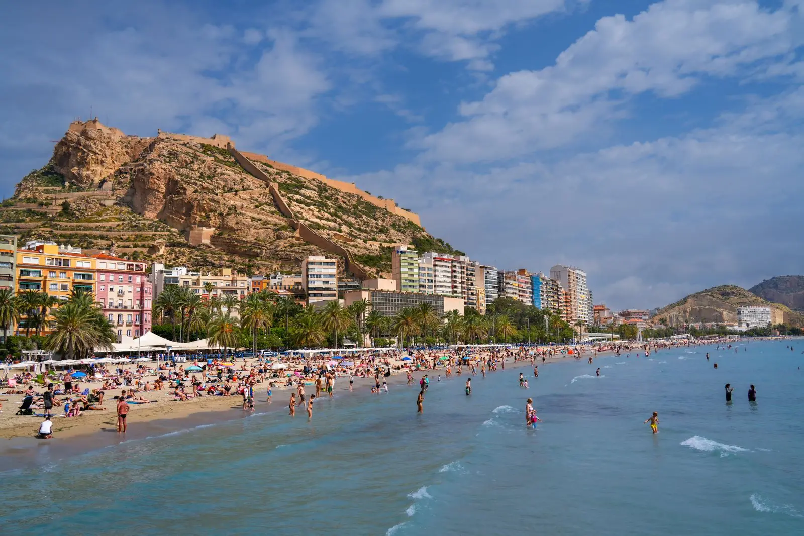 Druk zandstrand van Alicante met de kasteelrots Santa Bárbara