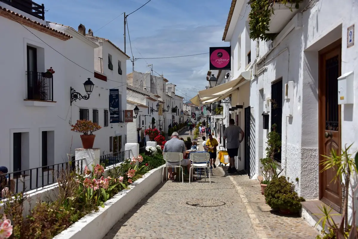 Smal geplaveid steegje met witte huizen en bloemen in Altea