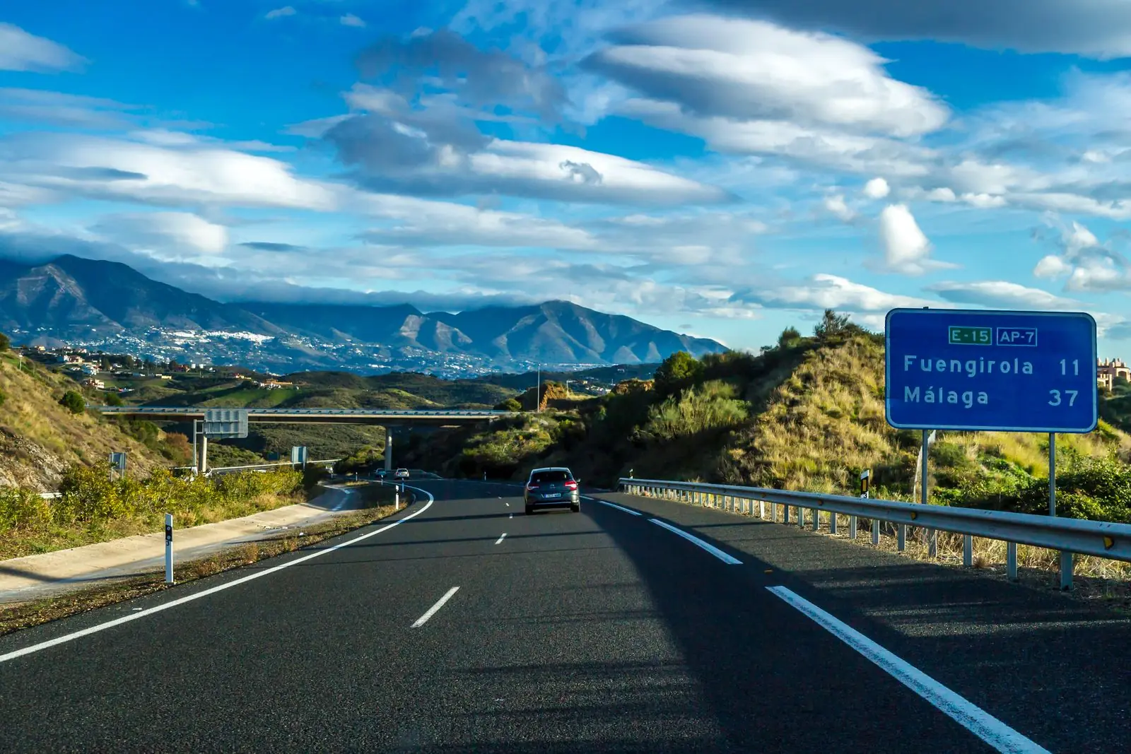 Snelweg AP-7 bij Fuengirola met bergen en een blauw verkeersbord