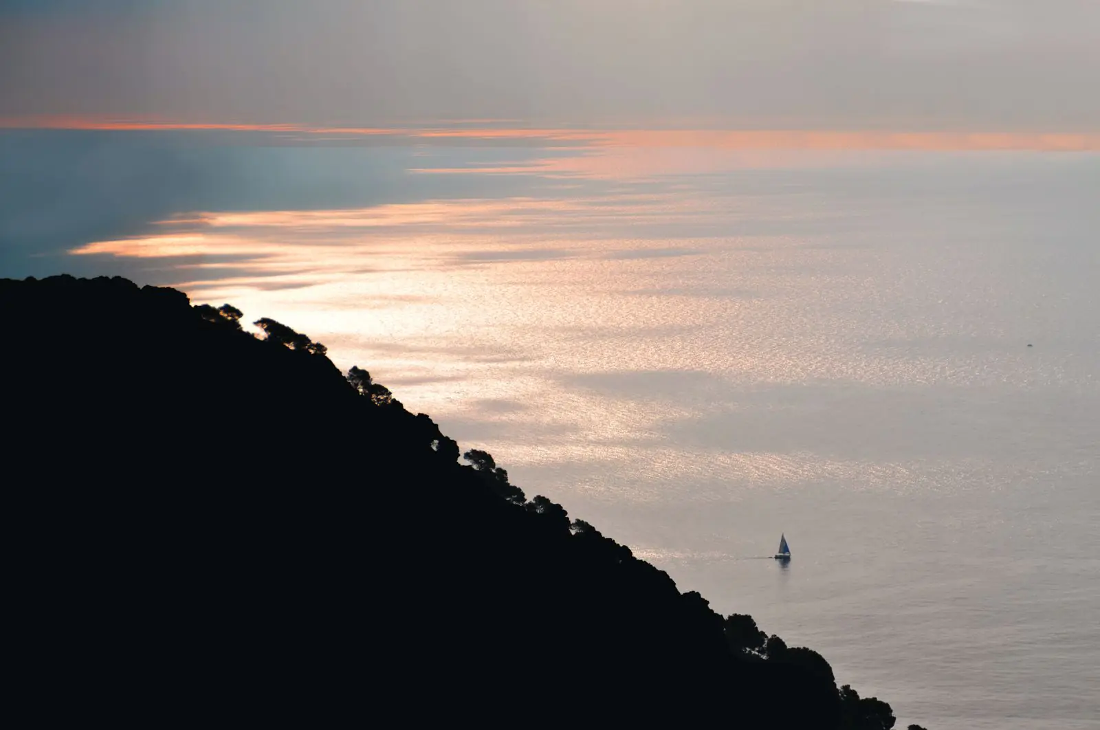 Zeilboot bij zonsondergang op zee voor de kust van Begur