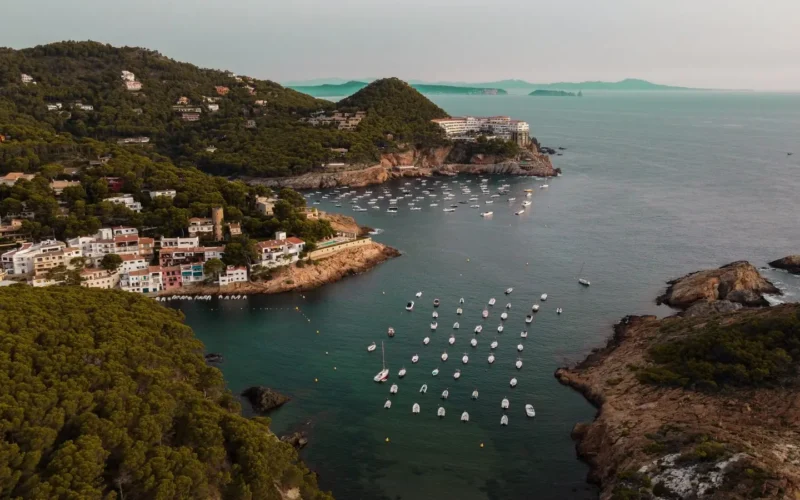 Luchtfoto van de baai Sa Tuna met bootjes, huizen en groene heuvels