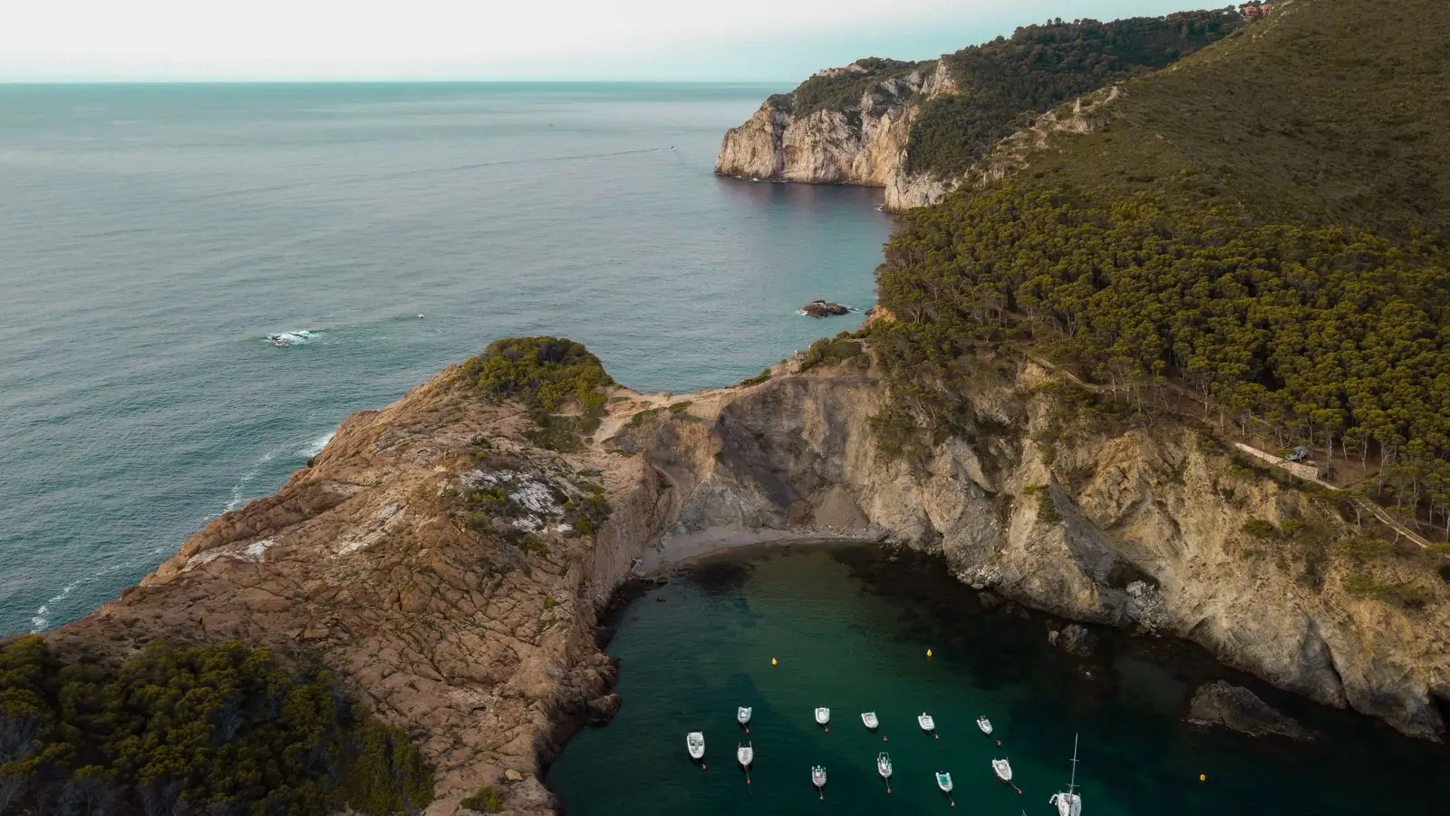 Luchtfoto van de baai Sa Tuna met bootjes en steile rotsen