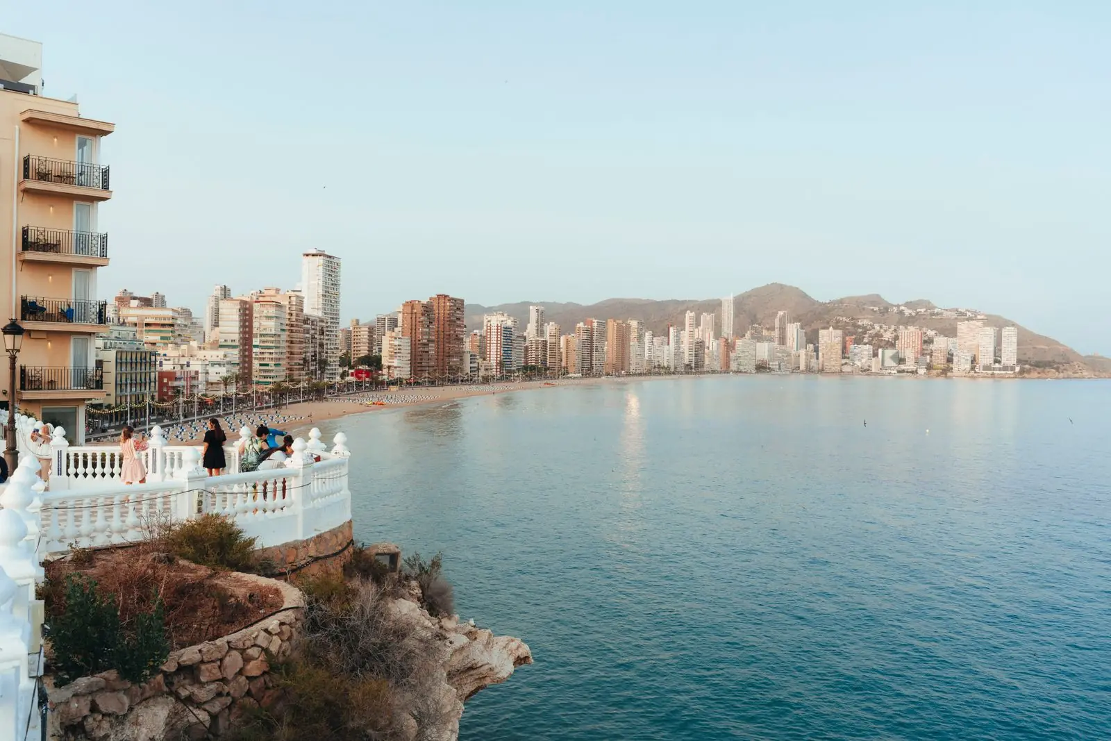 Uitkijkpunt met witte balustrade boven zee met de skyline van Benidorm