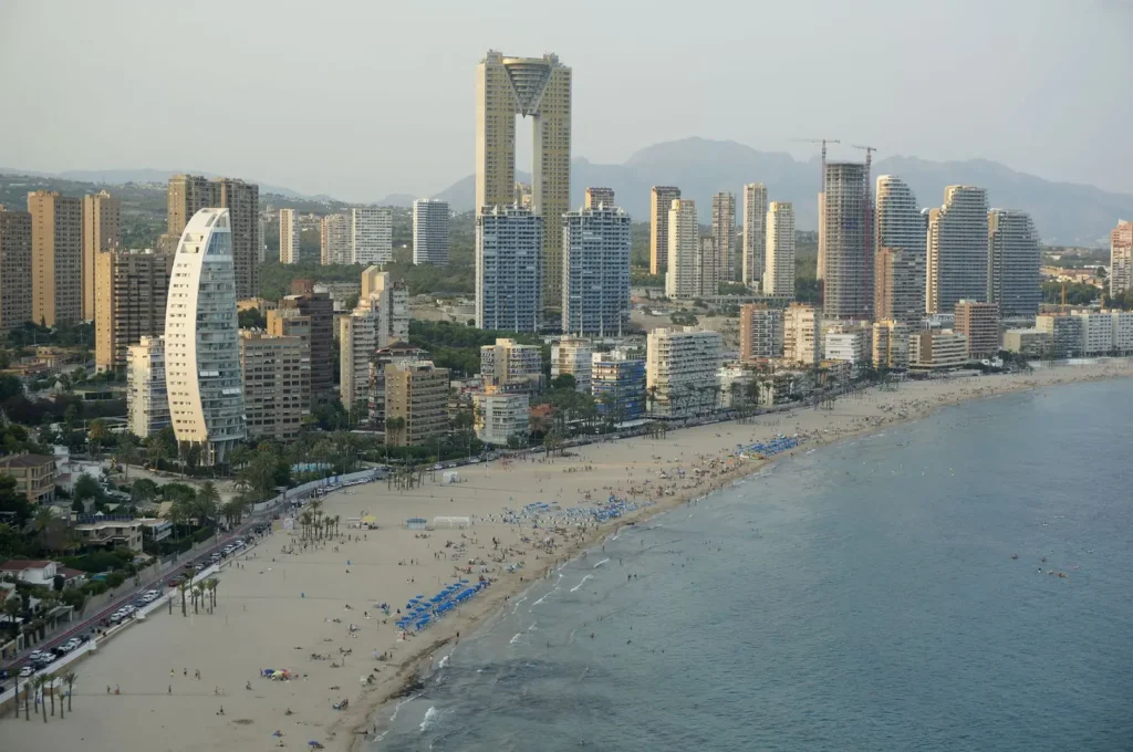 Luchtfoto van het drukke strand van Benidorm met hoge torens langs de boulevard