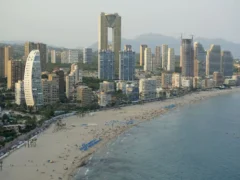 Luchtfoto van het drukke strand van Benidorm met hoge torens langs de boulevard