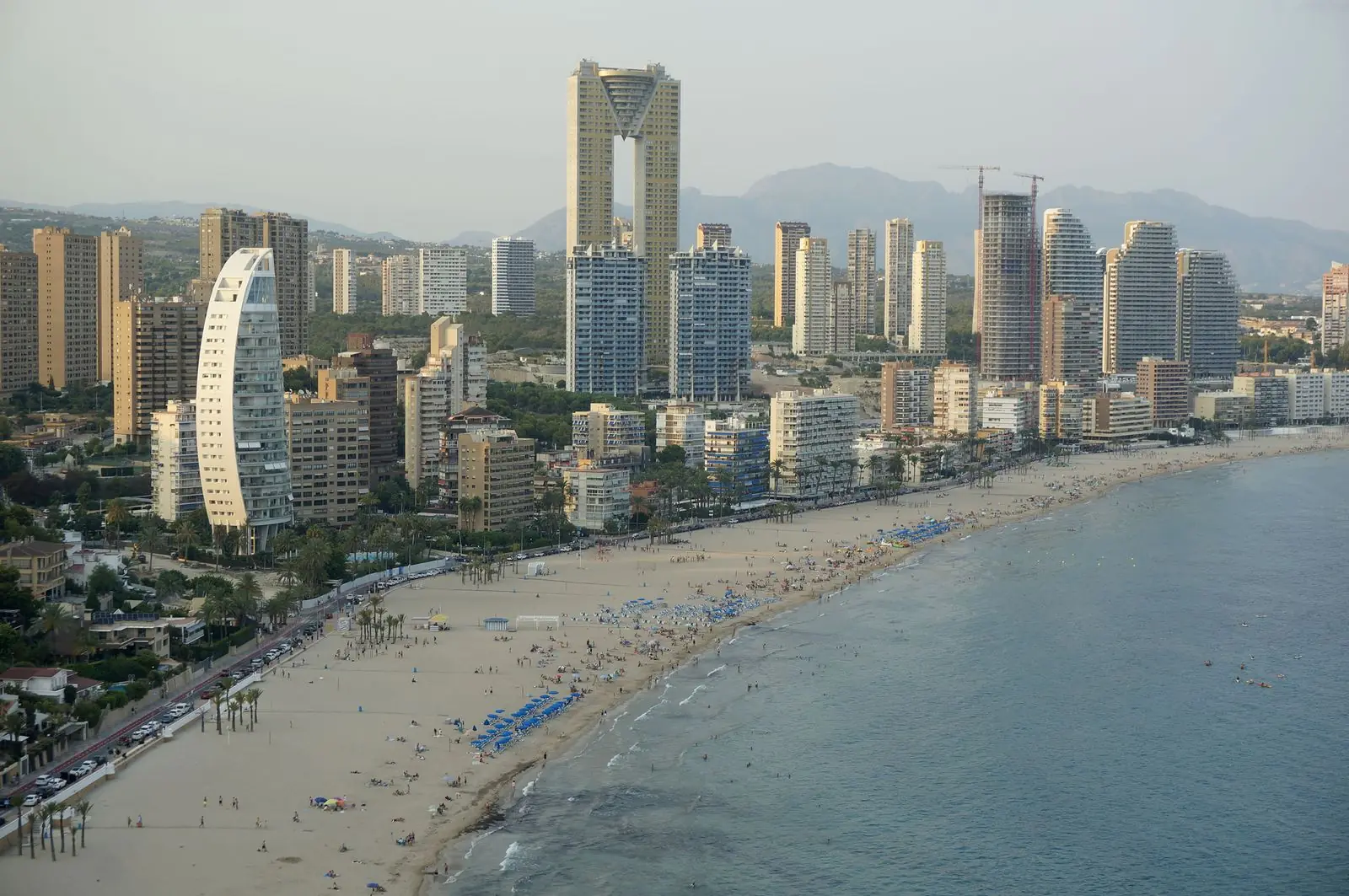 Luchtfoto van het drukke strand van Benidorm met hoge torens langs de boulevard