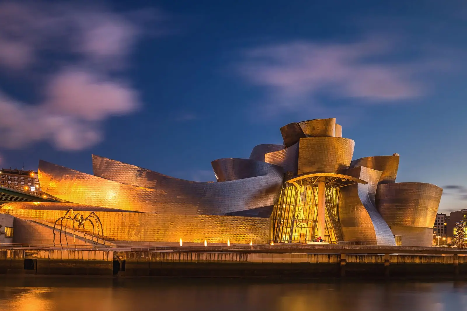 Het verlichte Guggenheim Museum in de avond, weerspiegeld in het water