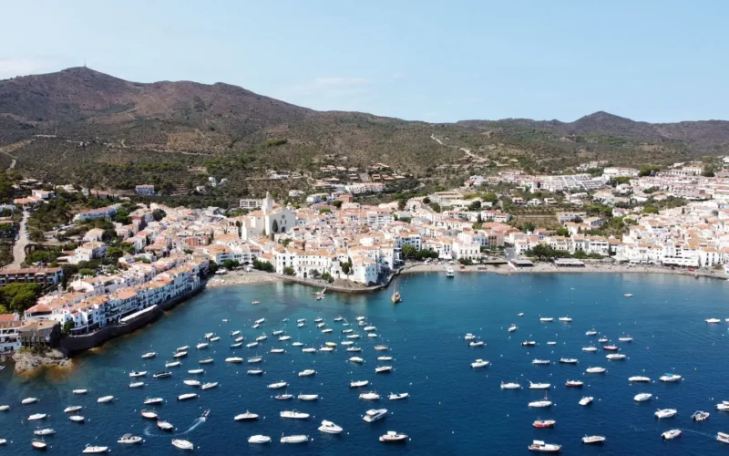 Luchtfoto van Cadaqués met witte huizen rond een baai vol boten