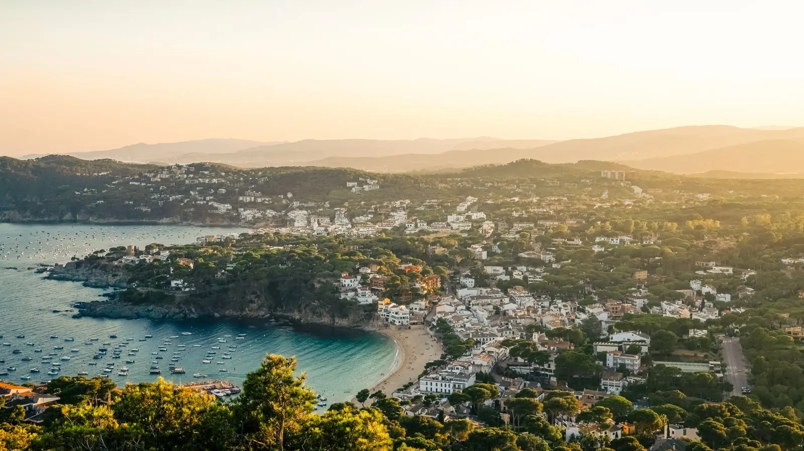 Luchtfoto van een baai met strand en groene heuvels bij zonsondergang