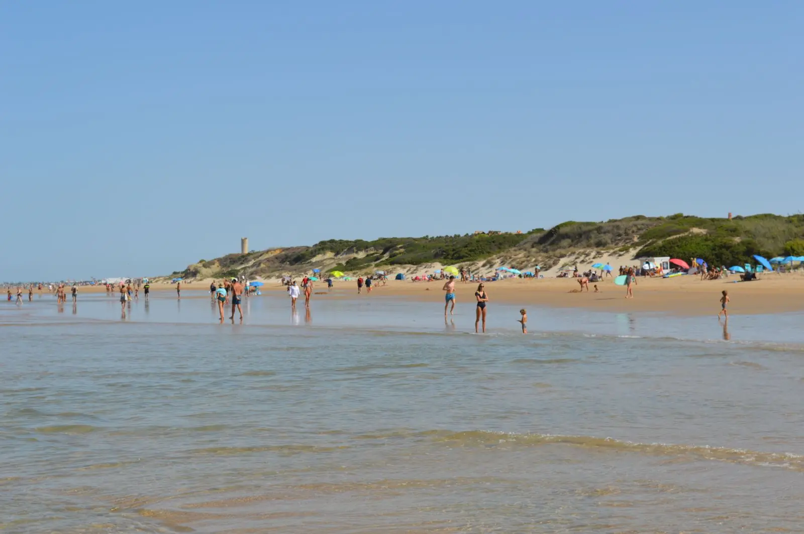 Breed zandstrand aan de Costa de la Luz met een toren op de begroeide kliffen