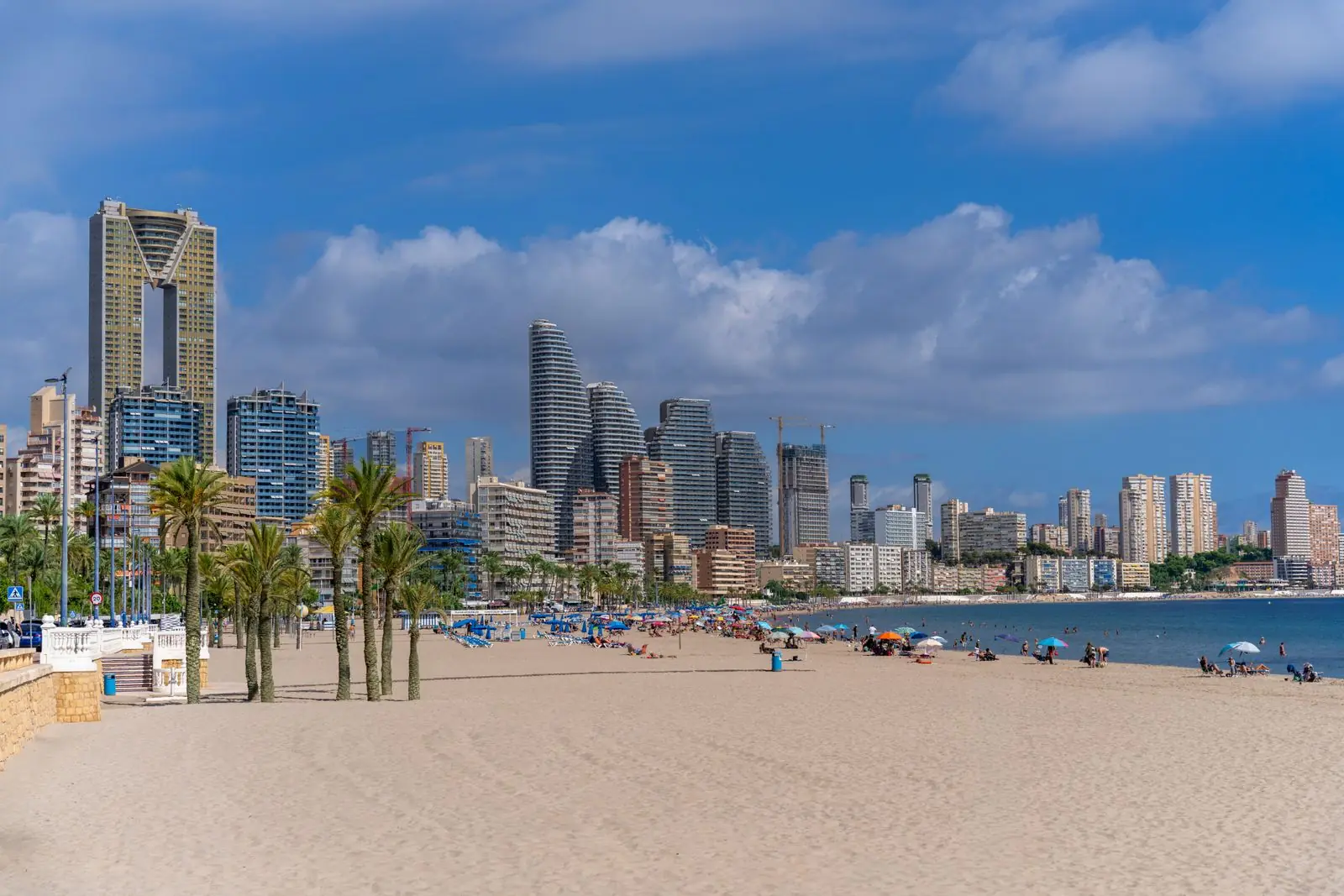 Breed zandstrand met palmbomen voor de hoogbouw van Benidorm