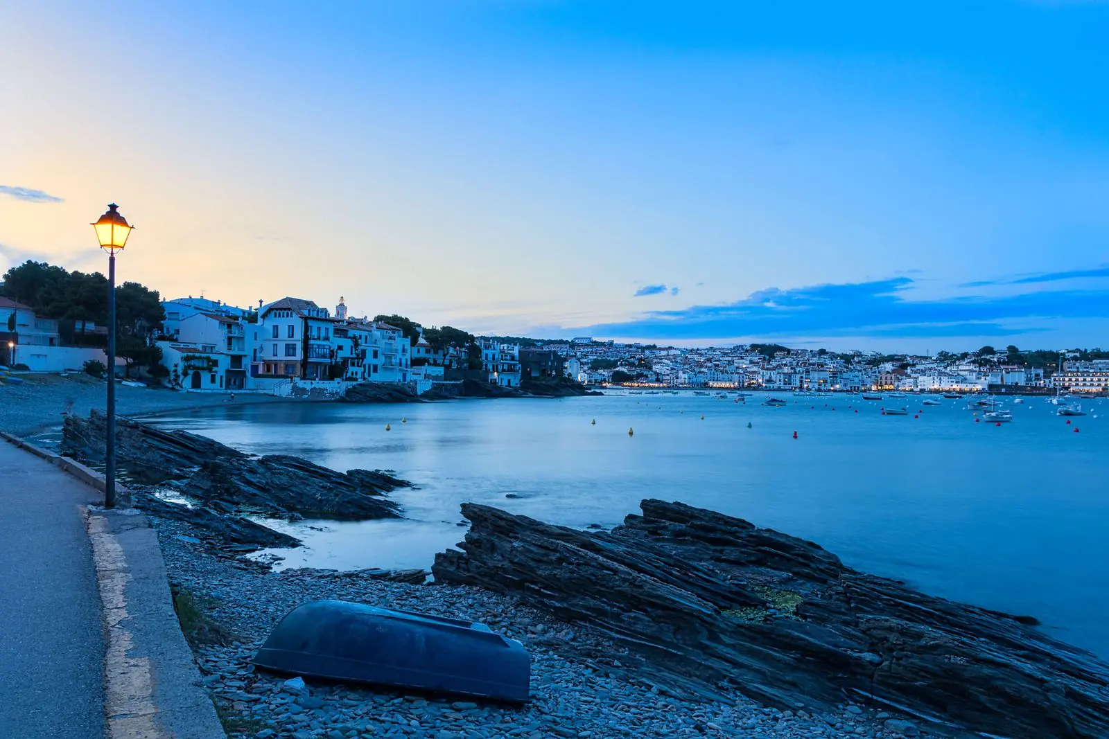 Kustpad langs de baai van Cadaqués met witte huizen in de avond