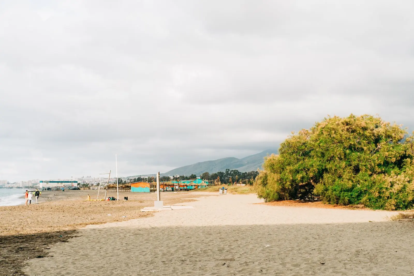 Zandstrand aan de Costa del Sol met groen en bewolkte lucht