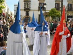 Processie met nazarenos in witte en blauwe puntkappen in een Spaanse straat