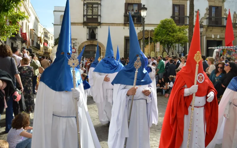 Processie met nazarenos in witte en blauwe puntkappen in een Spaanse straat