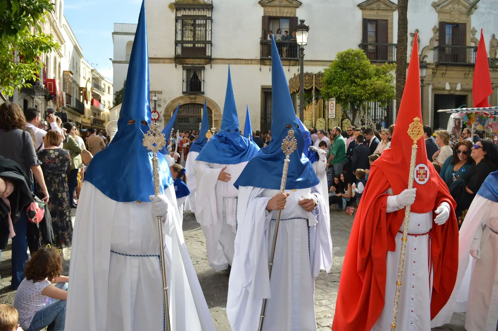 Processie met nazarenos in witte en blauwe puntkappen in een Spaanse straat