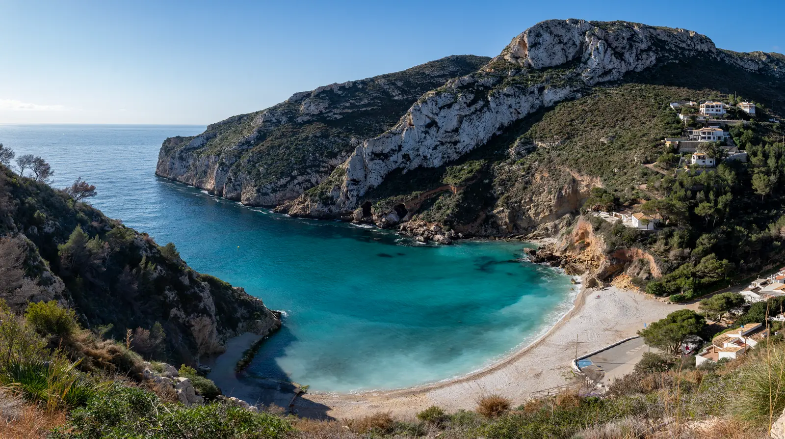 Kleine baai met kiezelstrand tussen beboste kliffen bij Jávea