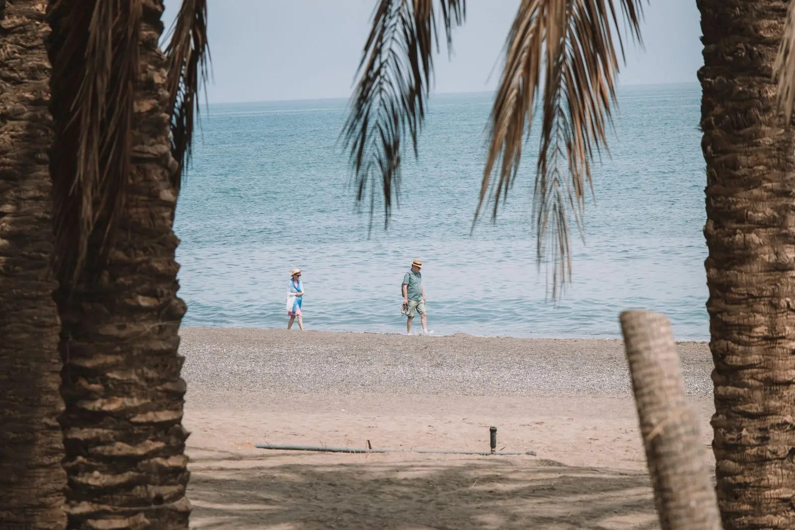 Stel wandelt over een zandstrand in Málaga tussen palmbomen