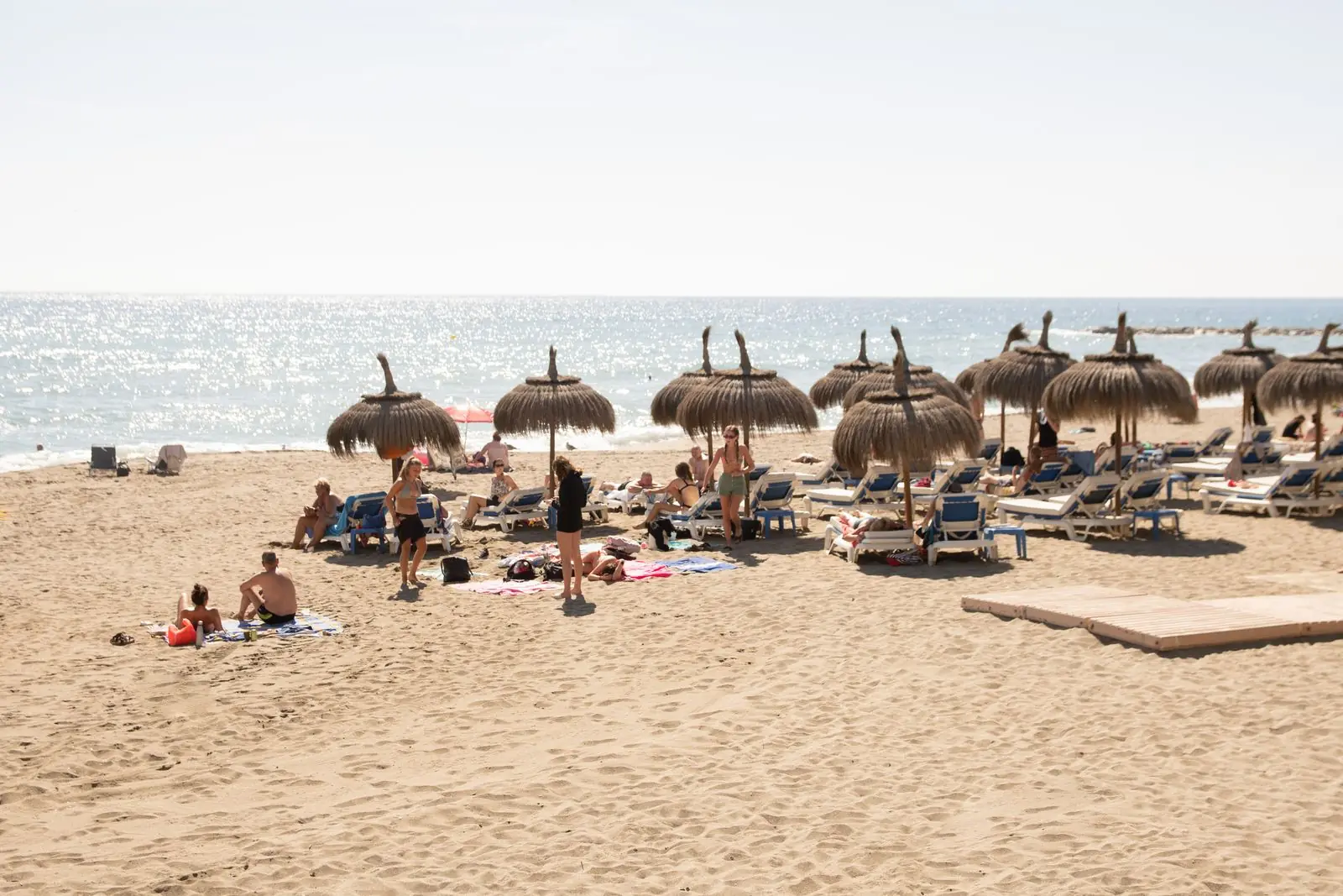 Strand in Marbella met rieten parasols en ligbedden aan zee
