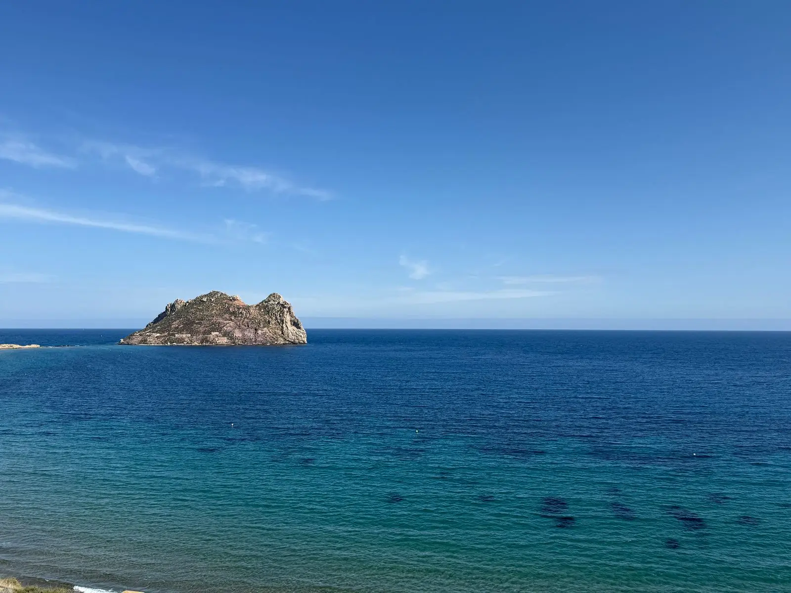 Klein rotseiland in een kalme blauwe zee bij Mazarrón