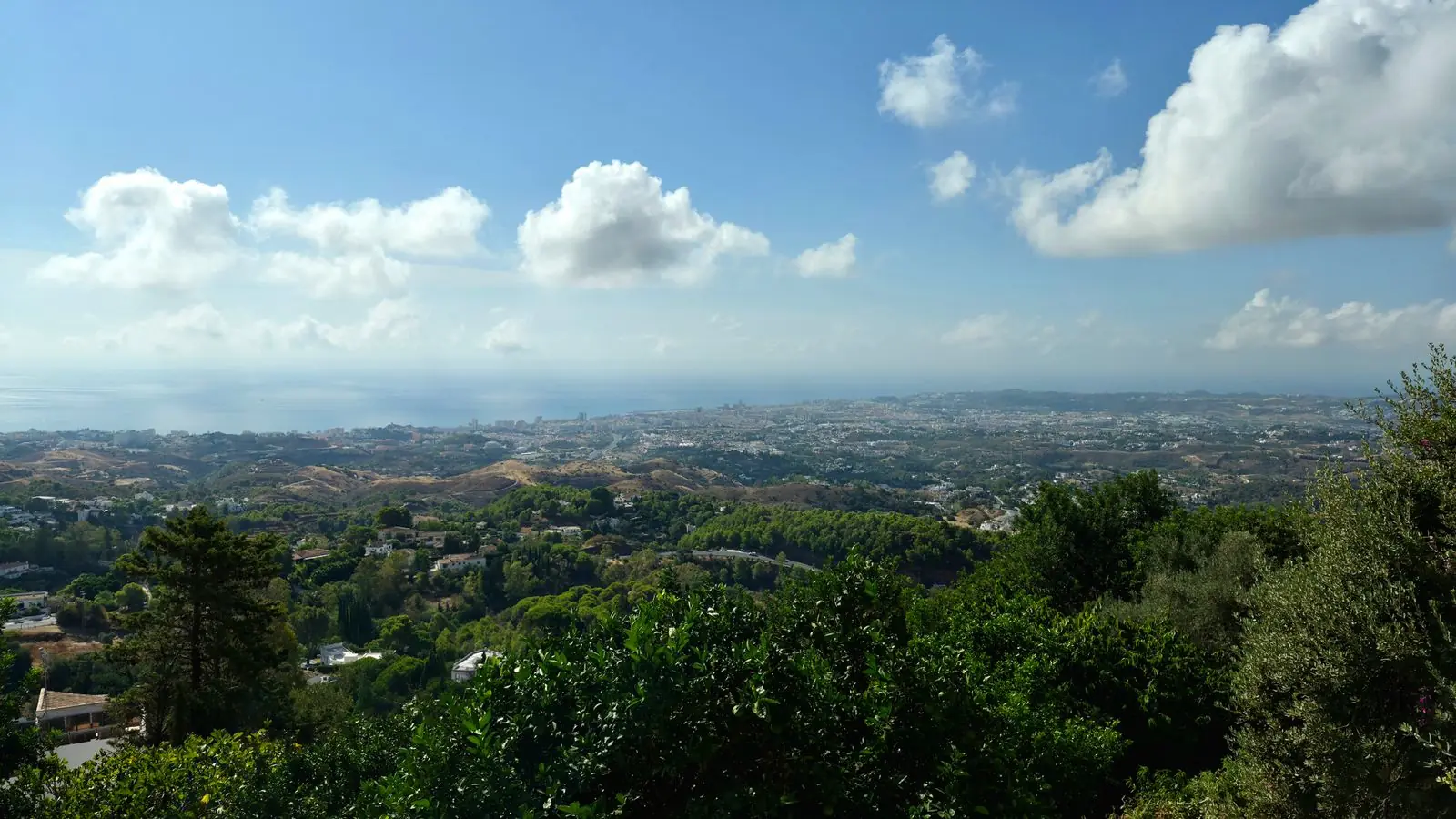 Uitzicht vanaf Mijas over groene heuvels naar de kust en de zee