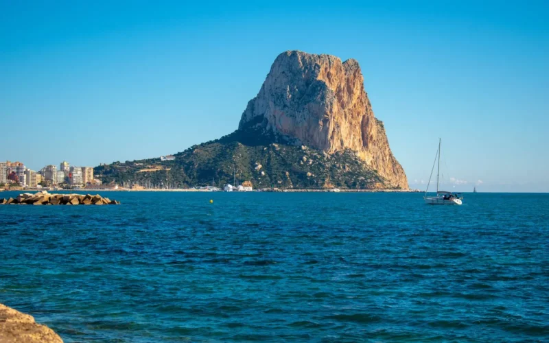 De Peñón de Ifach rijst op uit zee met een zeilboot ervoor