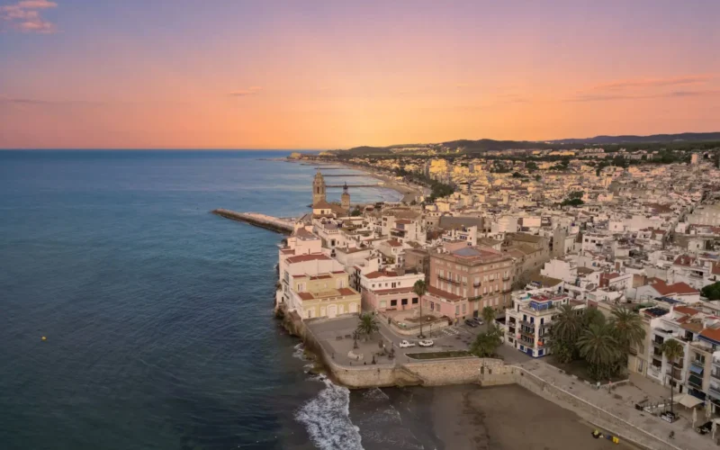Luchtfoto van Sitges met de kerk op de rots en de kust bij zonsondergang