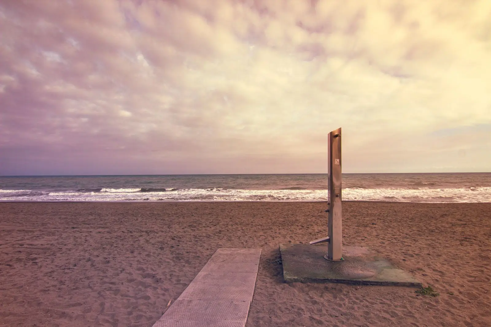 Strand van Torremolinos met golven en een stranddouche bij bewolking